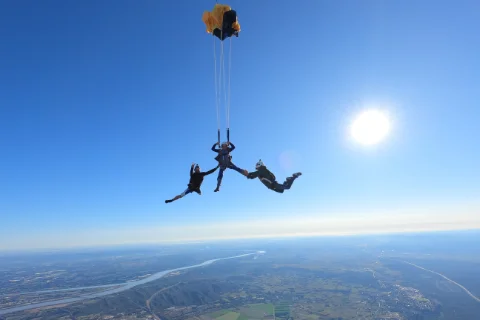Élève en saut d'initiation avec deux moniteurs Volomax en chute libre à Pujaut